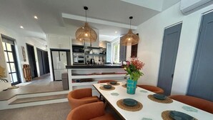 Une cuisine moderne avec des meubles blancs, un îlot central et des luminaires suspendus.