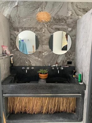 A bathroom with a marble wall, two round mirrors, a black sink with two faucets, a potted plant, and a straw brush rack. - 2BR Pool Villa Oasis Garden  V198 (Bophut)