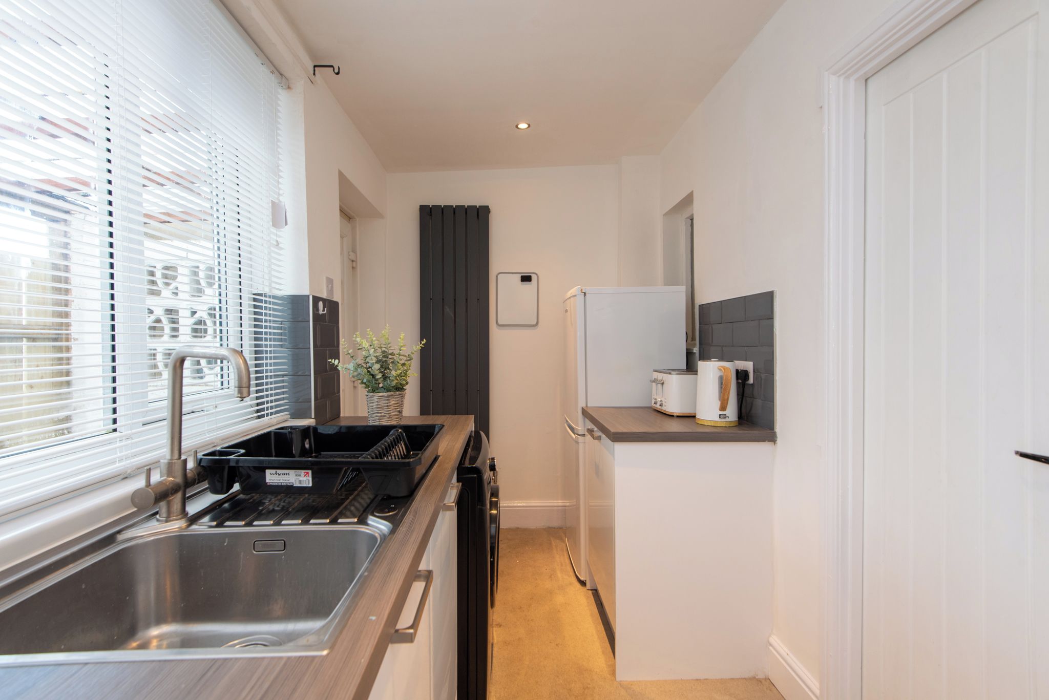 Een functionele keuken met een spoelbak, fornuis en kleine koelkast.