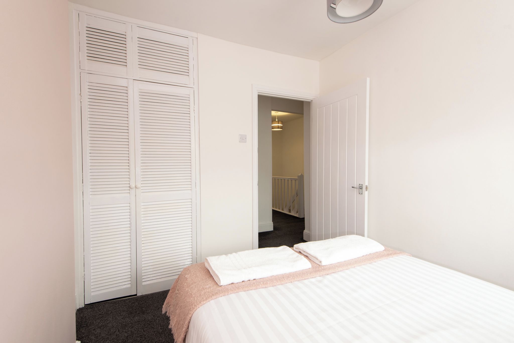 A bedroom with a bed, a closet, and a door leading to a staircase.