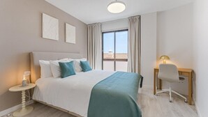 Ein Hotelzimmer mit einem Bett, einem Schreibtisch, einem Stuhl, einer Lampe und einem Vorhangfenster.