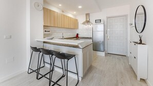 Eine moderne Küche mit einer zentralen Kochinsel, Barhocker, einer Mikrowelle und einem Kühlschrank.