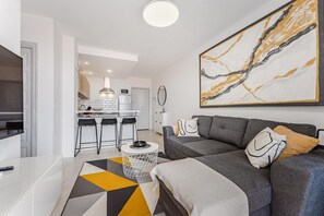 Un salon moderne avec un canapé, une table basse et un coin cuisine à l’arrière-plan.