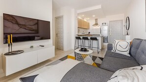 Ein modernes Wohnzimmer mit Fernseher, einer Couch und einem kleinen runden Tisch.