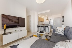 Un salon moderne avec un téléviseur, un canapé et une petite table ronde.