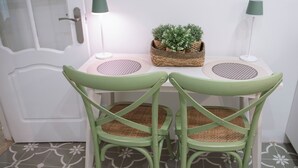 Un petit coin repas avec deux chaises vertes, une table blanche et deux lampes.