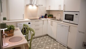 Une cuisine moderne avec des armoires blanches, une hotte de cuisinière en acier inoxydable, un four à micro-ondes encastré et un lave-vaisselle.