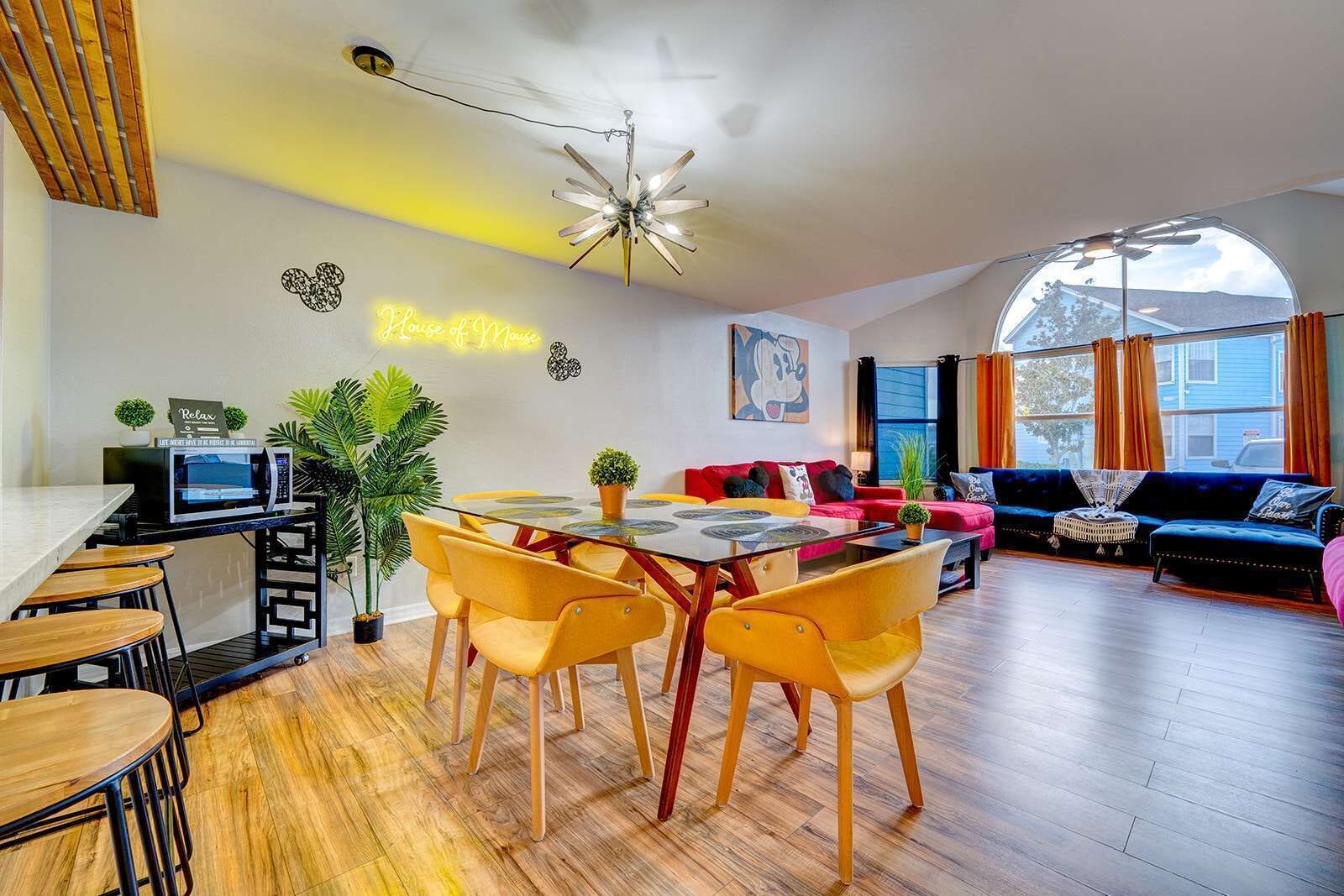 Spacious living and dining area with colorful seating and large arched window for natural light