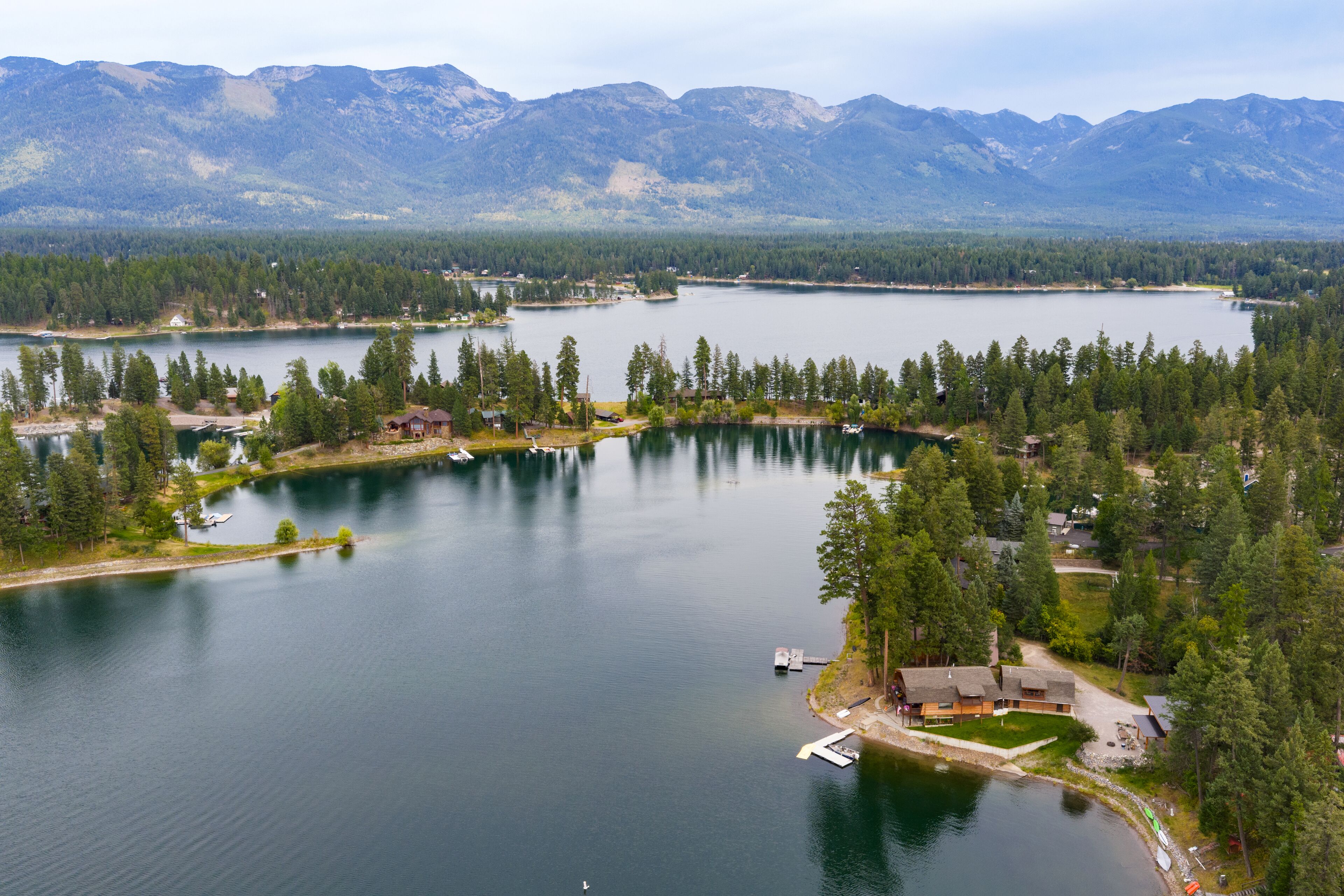 Une propriété au bord du lac, dotée de chalets, d’un quai et offrant une vue sur les montagnes.