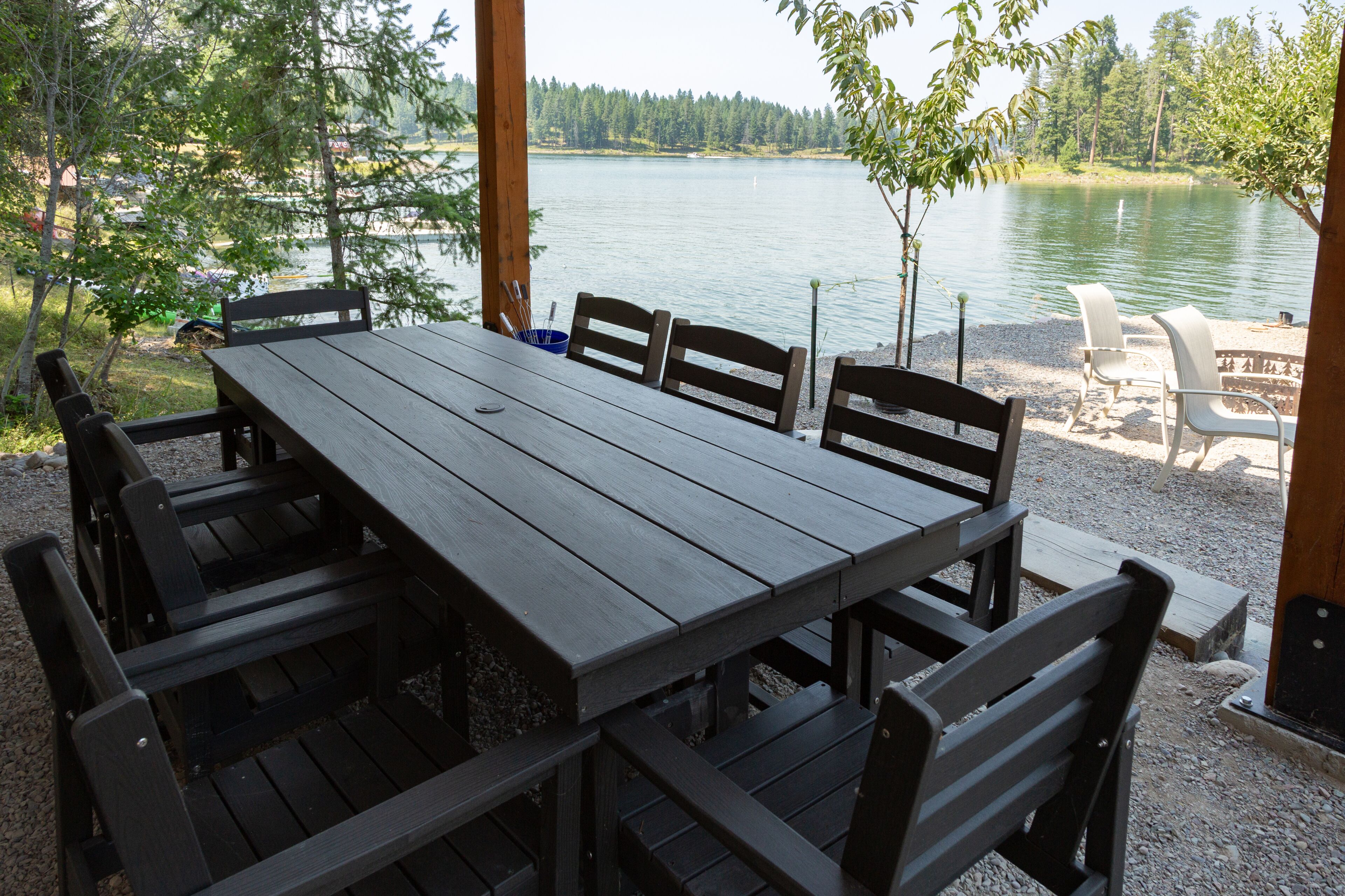 Un área de comedor al aire libre con una mesa y bancos de madera, con vistas a un lago.