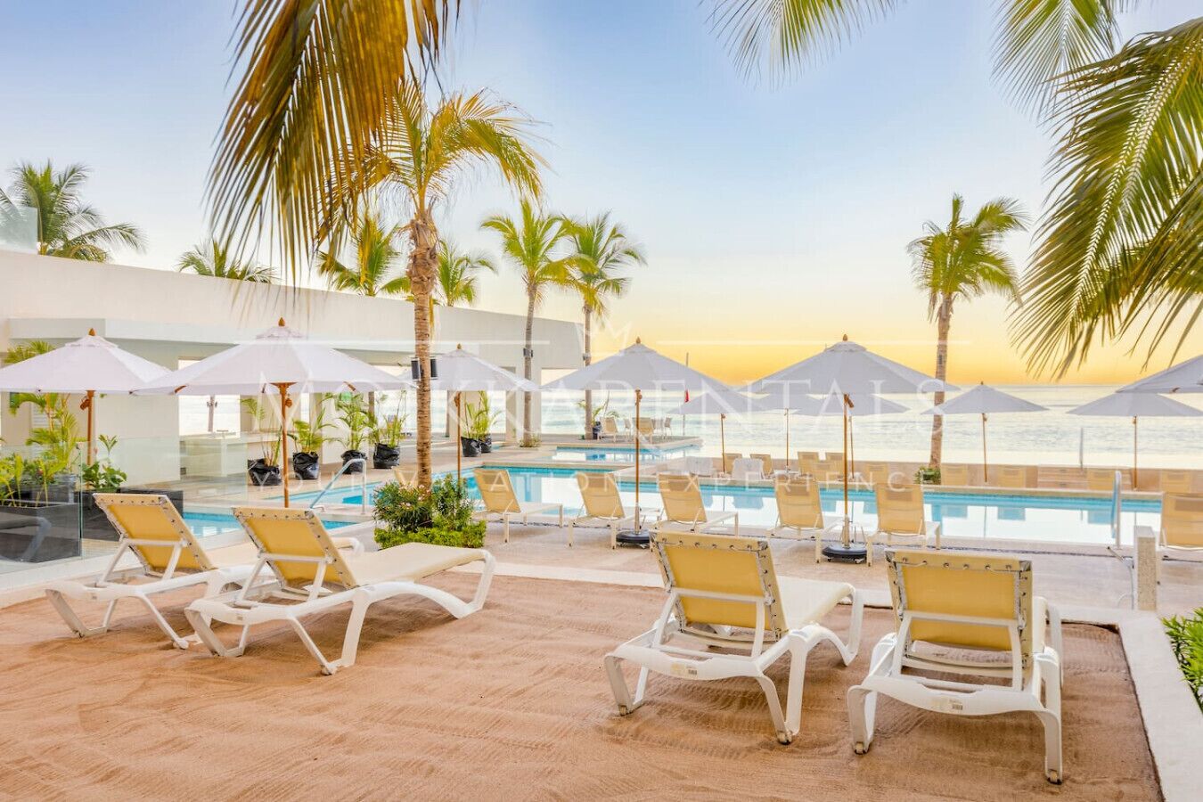 A poolside area with lounge chairs and umbrellas, overlooking a body of water.