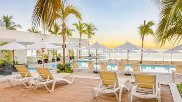 A poolside area with lounge chairs and umbrellas, overlooking a body of water.