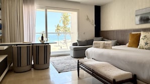 A modern hotel room with a bed, a sofa, a dining area, and a view of the beach. - Stylish Beachfront Studio by Moikkarentals (Puerto Vallarta)