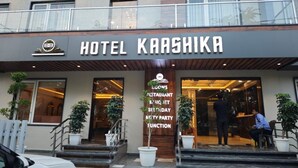 Hotel Kaashikas ydre, med en moderne facade, og et skilt der viser faciliteter som værelser, restaurant, festlokale, fødselsdage, mindre selskaber og arrangementer.