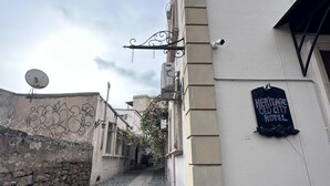 Un stretto vicolo acciottolato con un edificio sulla destra, che mostra un cartello per l'