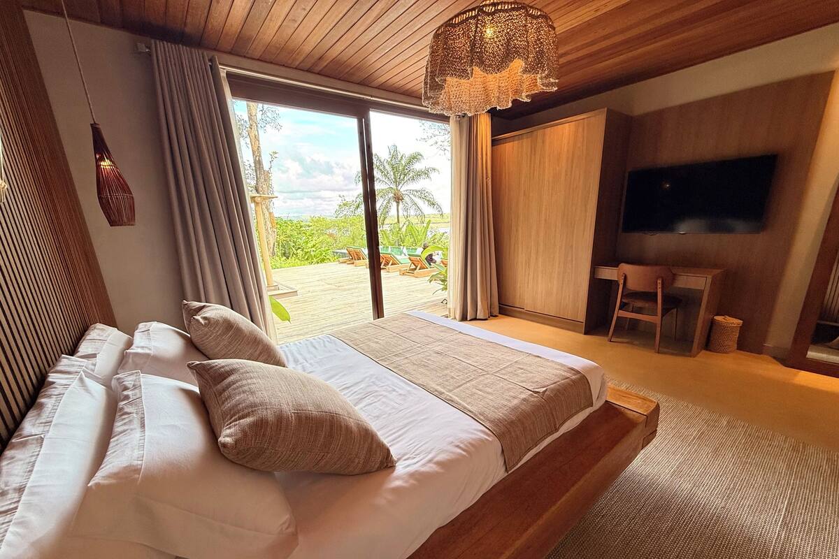 A bedroom with a large bed, a TV, and a view of the outdoors.