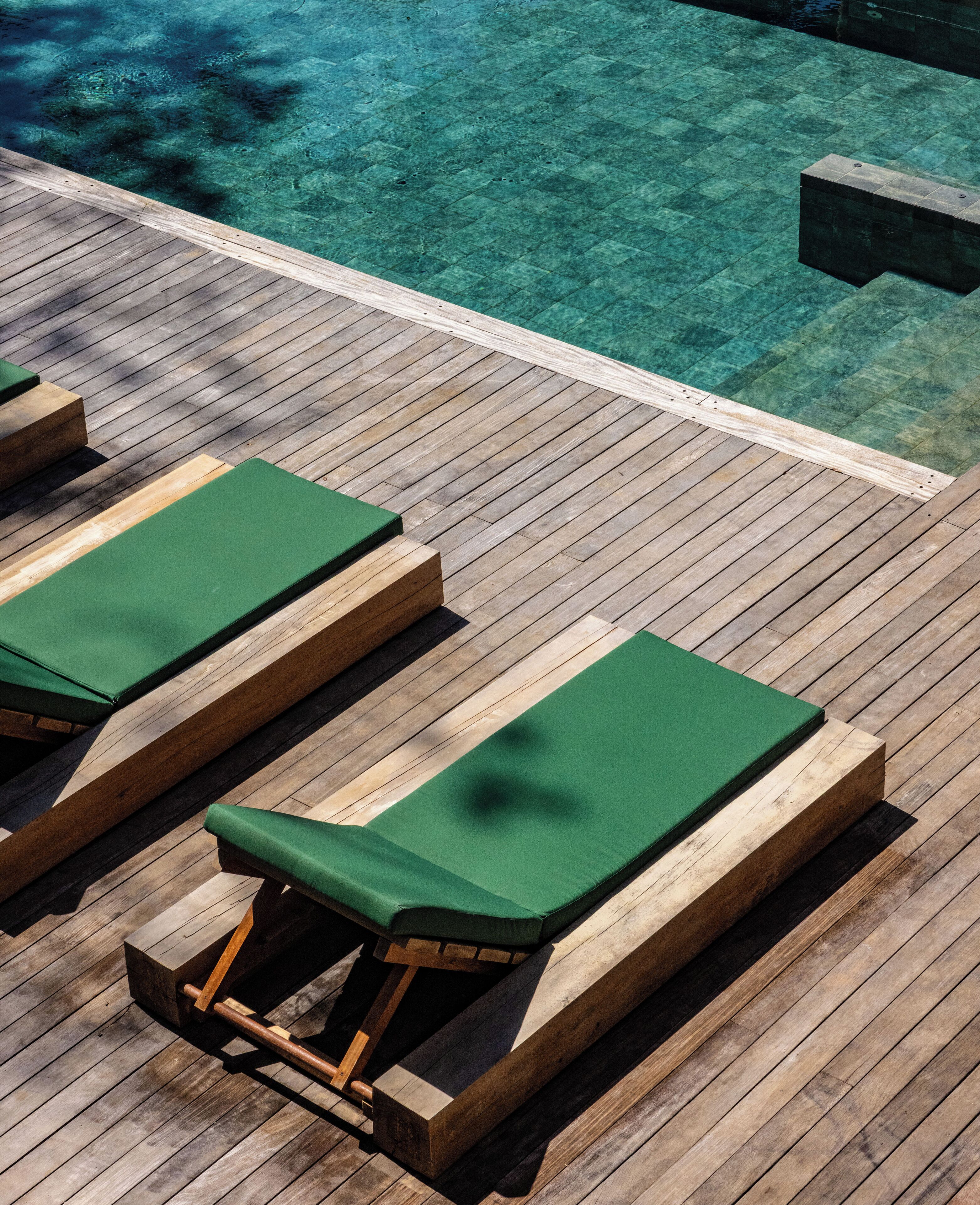 A wooden deck with lounge chairs and a pool.