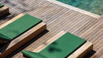 A wooden deck with lounge chairs and a pool.