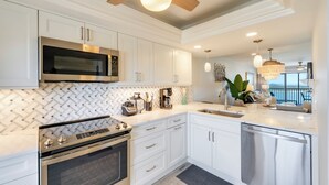 A modern kitchen with white cabinetry, stainless steel appliances, and a large island with a sink. - Gulf View! 2B/2B CONDO AT ISLANDS END 804! Pool! (Fort Myers Beach)