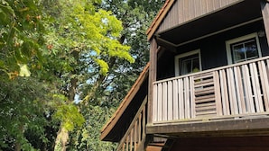 A wooden cabin with a balcony, surrounded by dense trees and a clear sky. - Fully furnished apartment with balcony on forest and dune area (Soest)