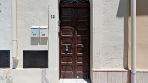 A brown door with a metal latch and a keyhole, flanked by two electrical boxes, one above and one below the door.