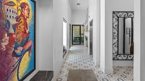 Un passadís amb un mural colorit, rajoles de terra amb un disseny i una porta metàl·lica decorativa.