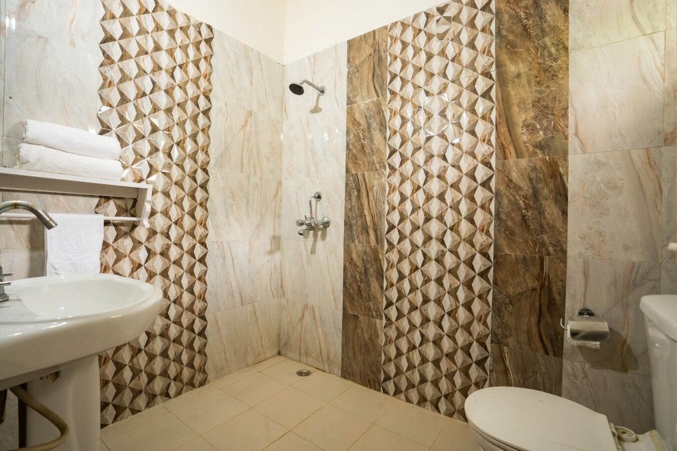 A bathroom with a sink, toilet, and shower. The walls have a geometric tile pattern.
