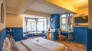 Une chambre à coucher avec un grand lit, un bureau et une chaise, ainsi qu’une fenêtre et des rideaux.