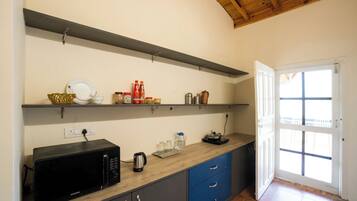 A kitchen with a microwave, kettle, and various kitchen items on shelves. There is a door leading to a balcony.
