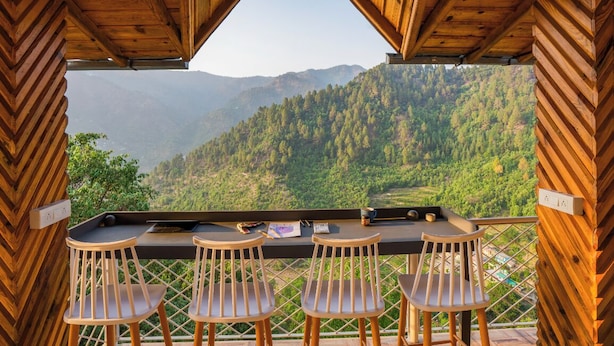 Une cabane en bois dotée d’un balcon donnant sur un paysage montagneux.