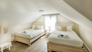 A bedroom with two beds, wooden headboards, a small bedside table, and a white bench.
