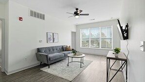 A modern living room with a grey sofa, a round coffee table, and a small side table with a plant. - Chic 2BR/2BA with Gym and Rooftop Access (Memphis)