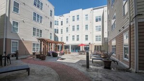 A courtyard with a pergola, outdoor seating, and a red umbrella. - Chic 2BR/2BA with Gym and Rooftop Access (Memphis)