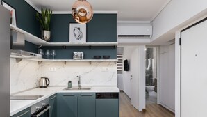 A modern kitchen with teal cabinets, a marble countertop, and a pendant light. - Aurora by halu (Thessaloniki)