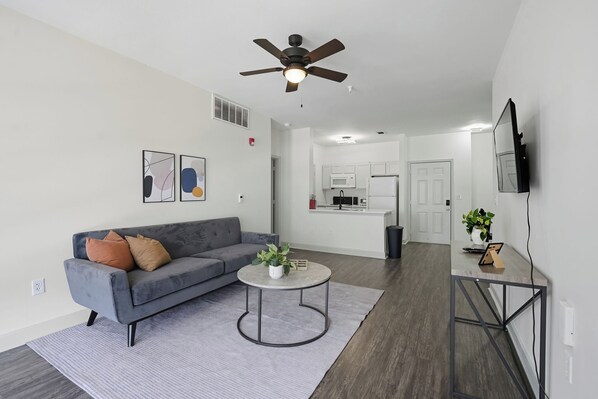 A modern living room with a gray sofa, a round coffee table, and a ceiling fan. - Spacious 2-Bedroom Apartment in Memphis (Memphis)