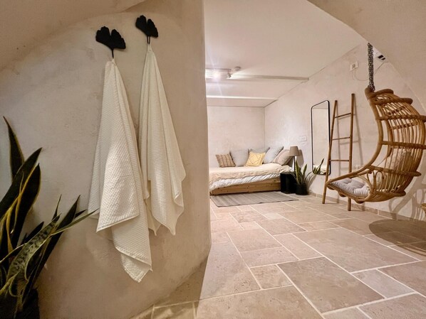A bedroom with a bed, a hanging chair, and a ladder.