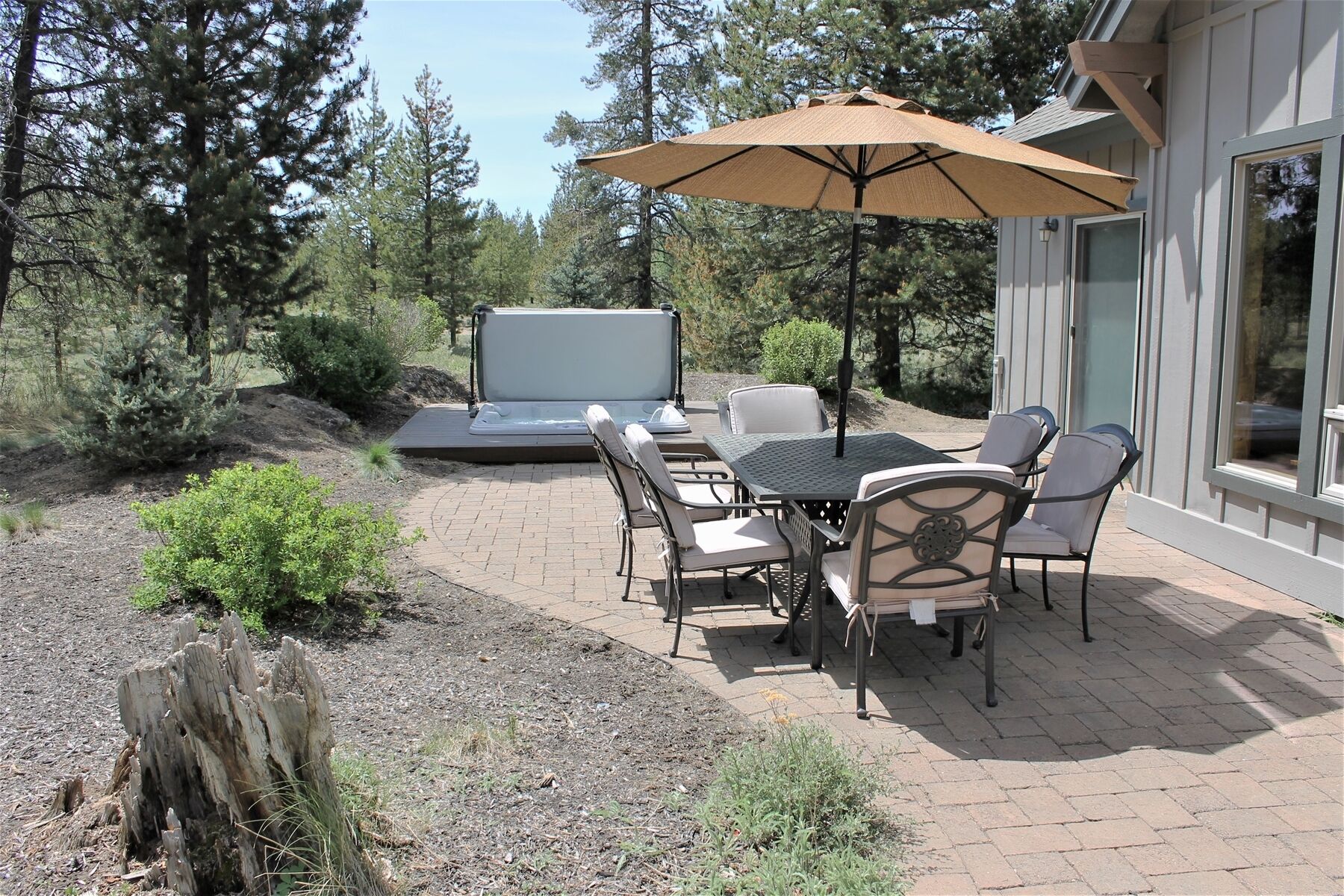 An outdoor patio with a table and chairs, a large umbrella, and a built-in barbecue grill.
