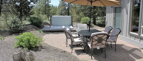An outdoor patio with a table and chairs, a large umbrella, and a built-in barbecue grill.