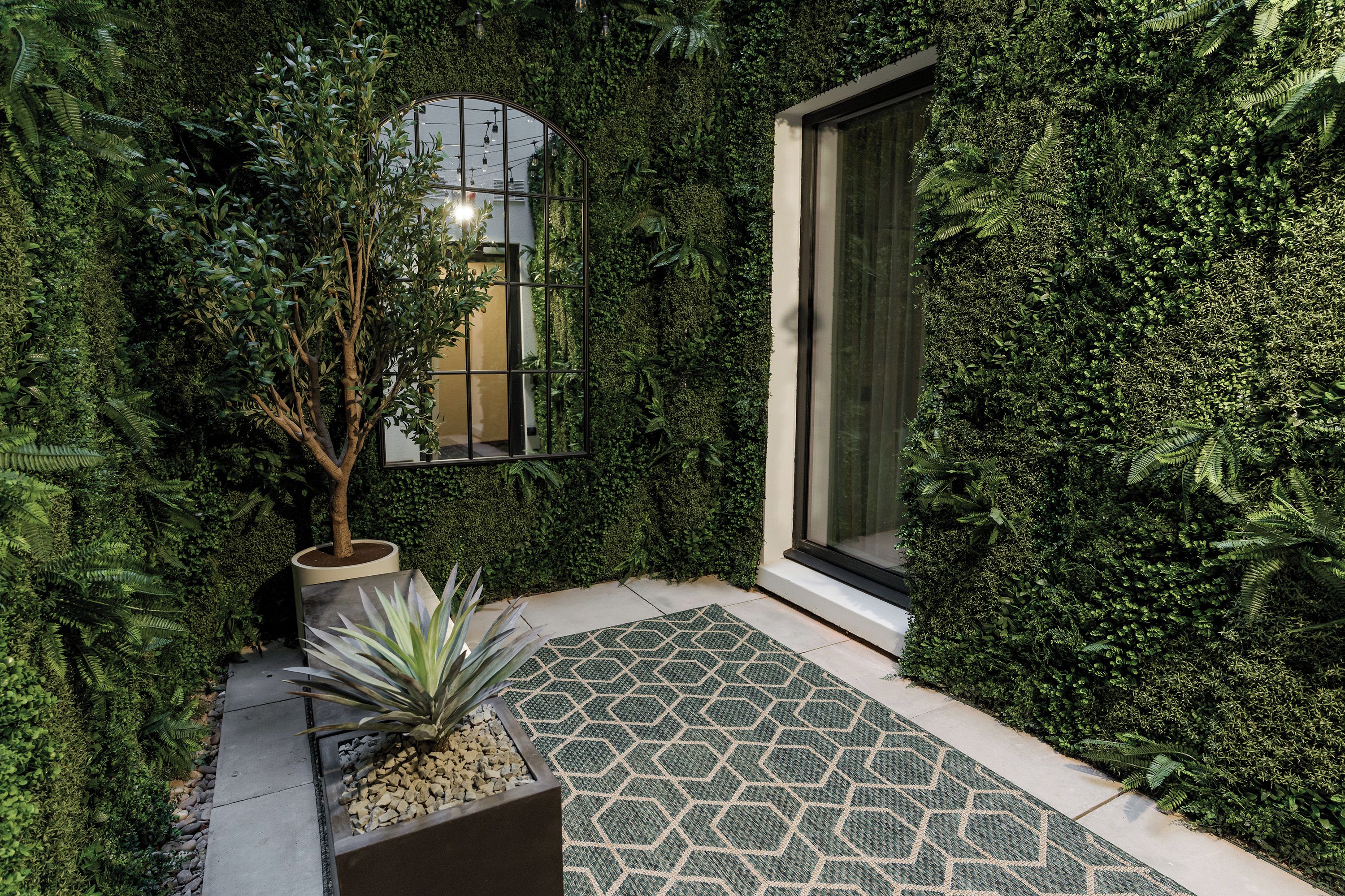 A garden area with a potted plant, a small tree, and a patterned tile floor.