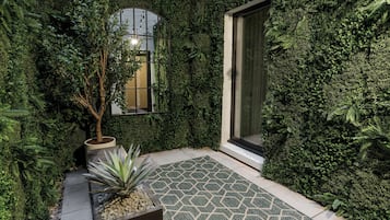 A garden area with a potted plant, a small tree, and a patterned tile floor.