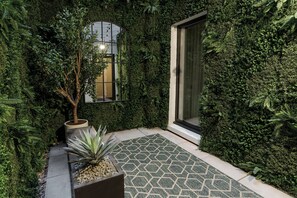 A garden area with a potted plant, a small tree, and a patterned tile floor. - onefifty fenchurch (London)