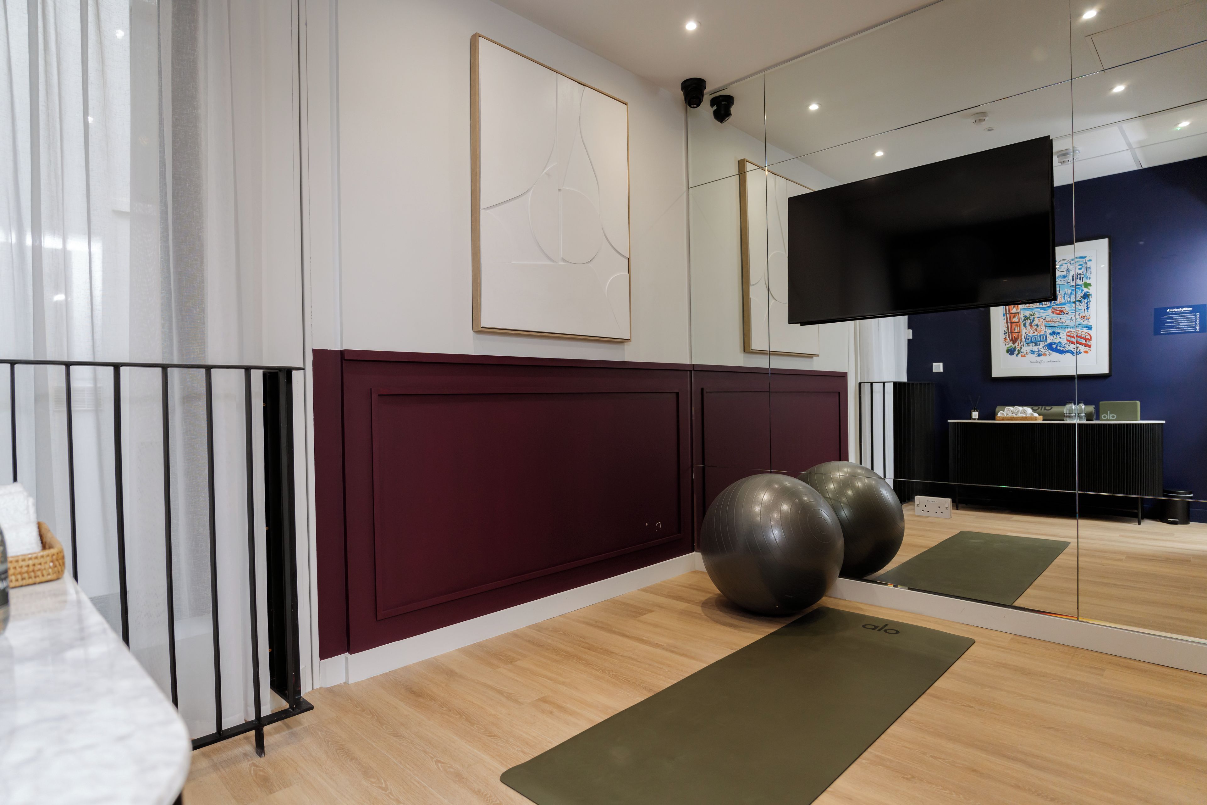 Een moderne fitnessruimte met trainingsapparatuur, een grote spiegel en kunstwerken aan de muur.