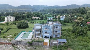 Un edificio a più piani con piscina, immerso nel verde e circondato da colline.