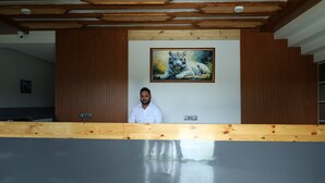 Un'area reception con scrivania in legno, un grande quadro che raffigura una tigre sulla parete e un design moderno del soffitto.