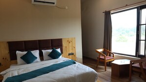 Una camera d'albergo con un letto, una sedia, un tavolino e una finestra vista.