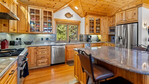 Un'ampia cucina con mobili in legno, un piano di lavoro in granito, elettrodomestici in acciaio inossidabile e una grande isola con posti a sedere.