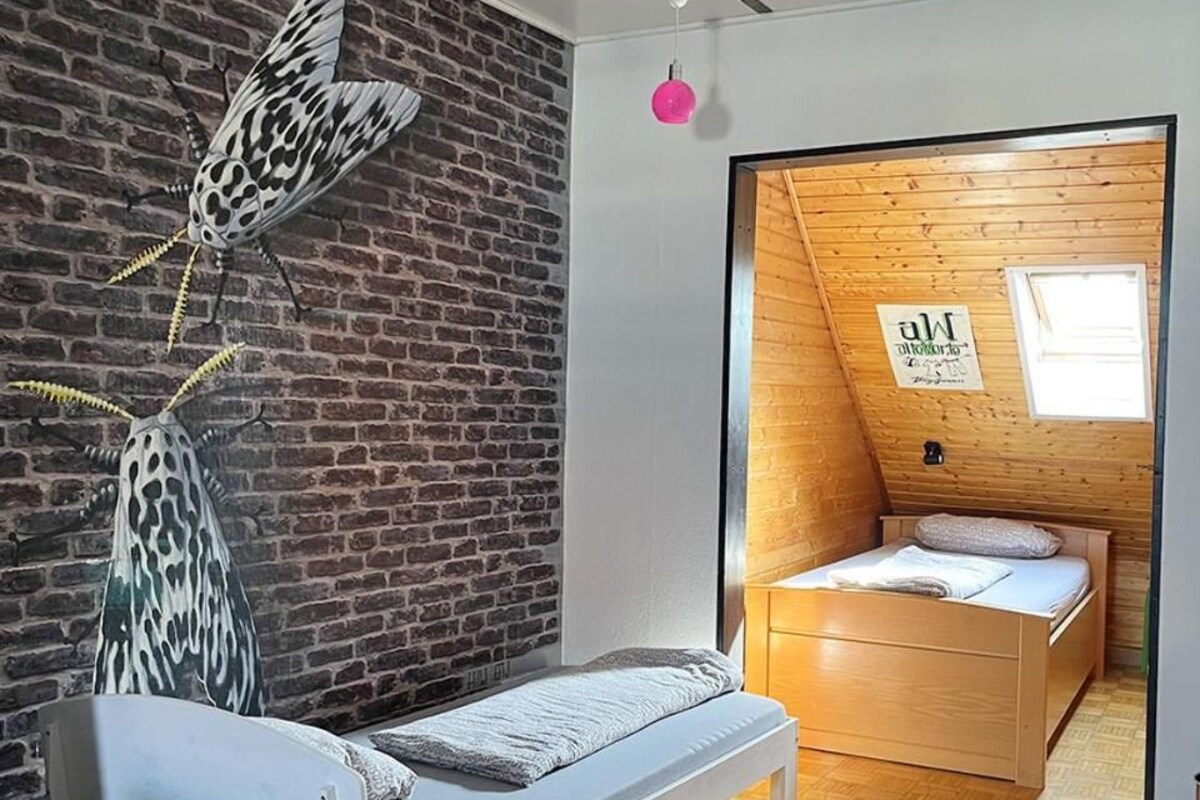 Una camera da letto con un letto, una panca, una parete in mattoni con decorazioni e un soffitto in legno.