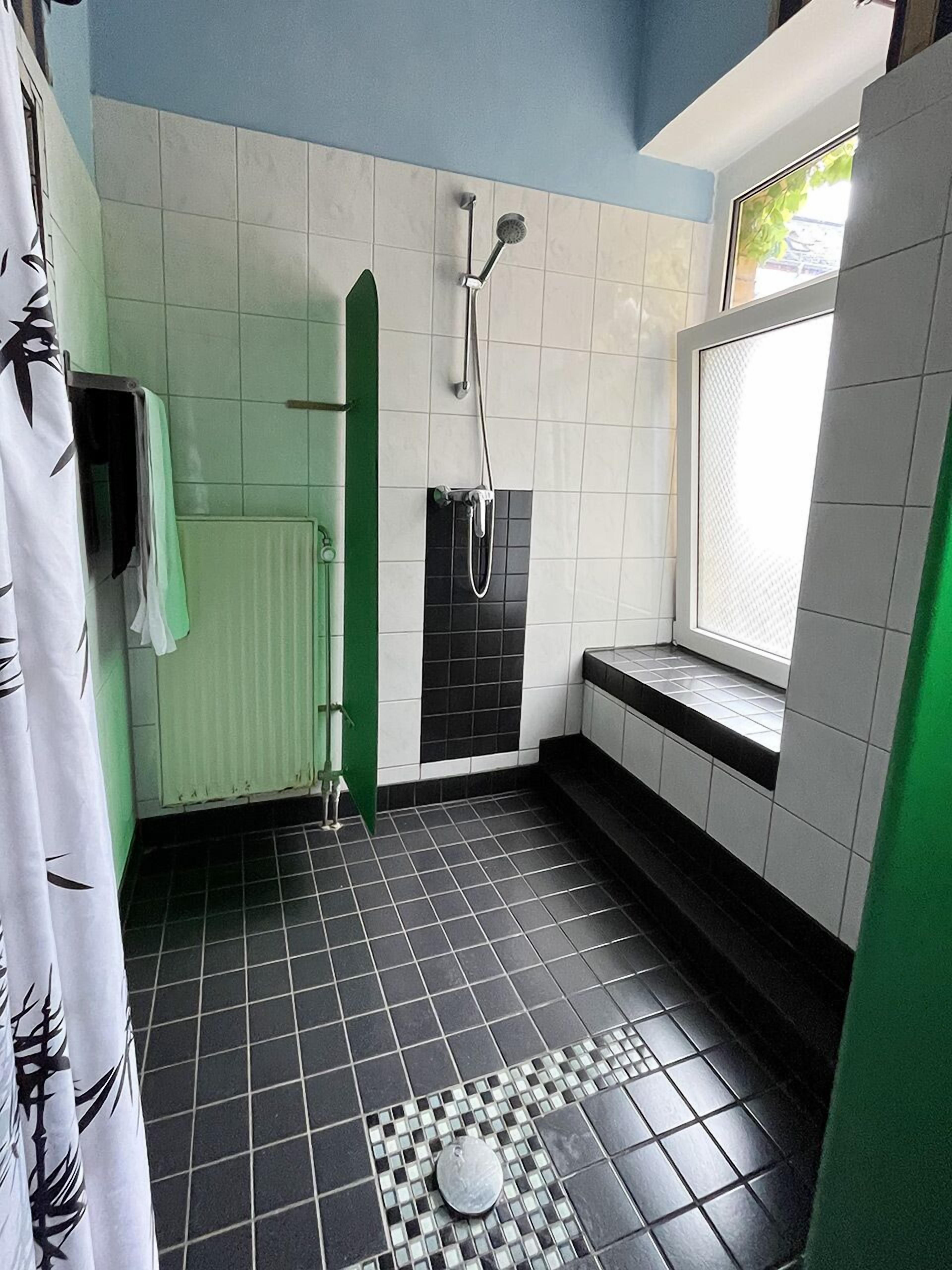 Un baño con ducha, inodoro y ventana.