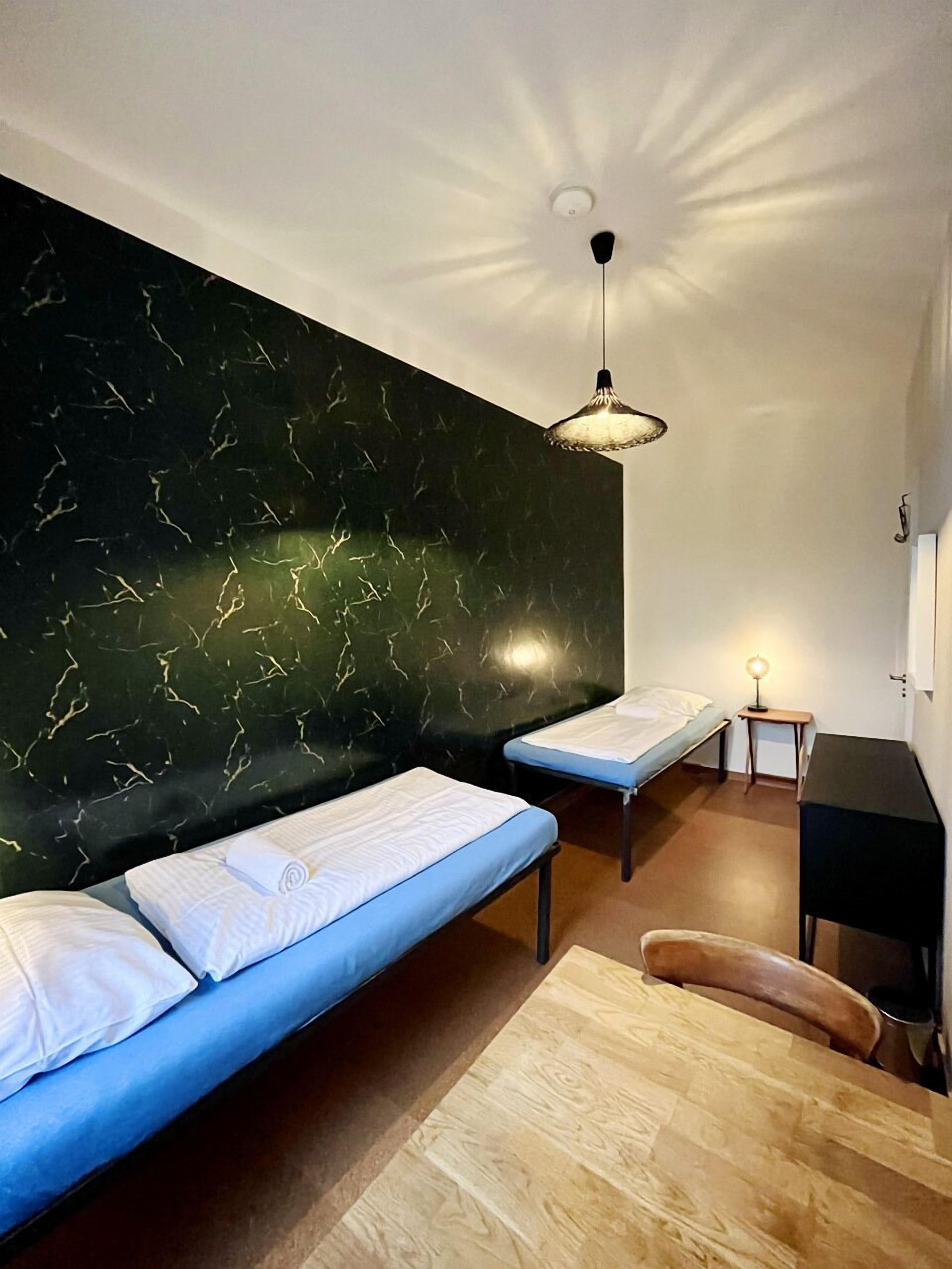 Ein Zimmer mit dunkler Marmorwand, einem blauen Sofa, einem Holztisch und einem kleinen Schreibtisch mit einer Lampe.
