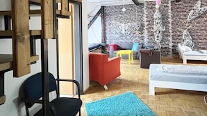 A modern interior with a staircase, a blue rug, and a brick wall with hanging decorations. - Homeplanet Hostel (Leipzig)